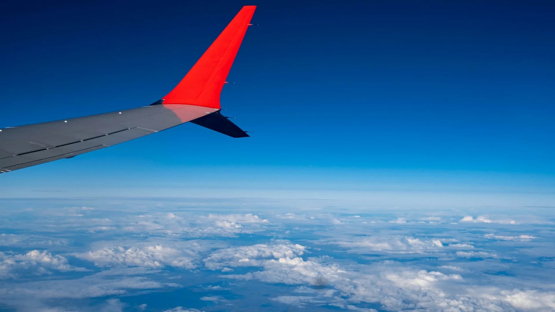Airplane wing above the clouds at sunset