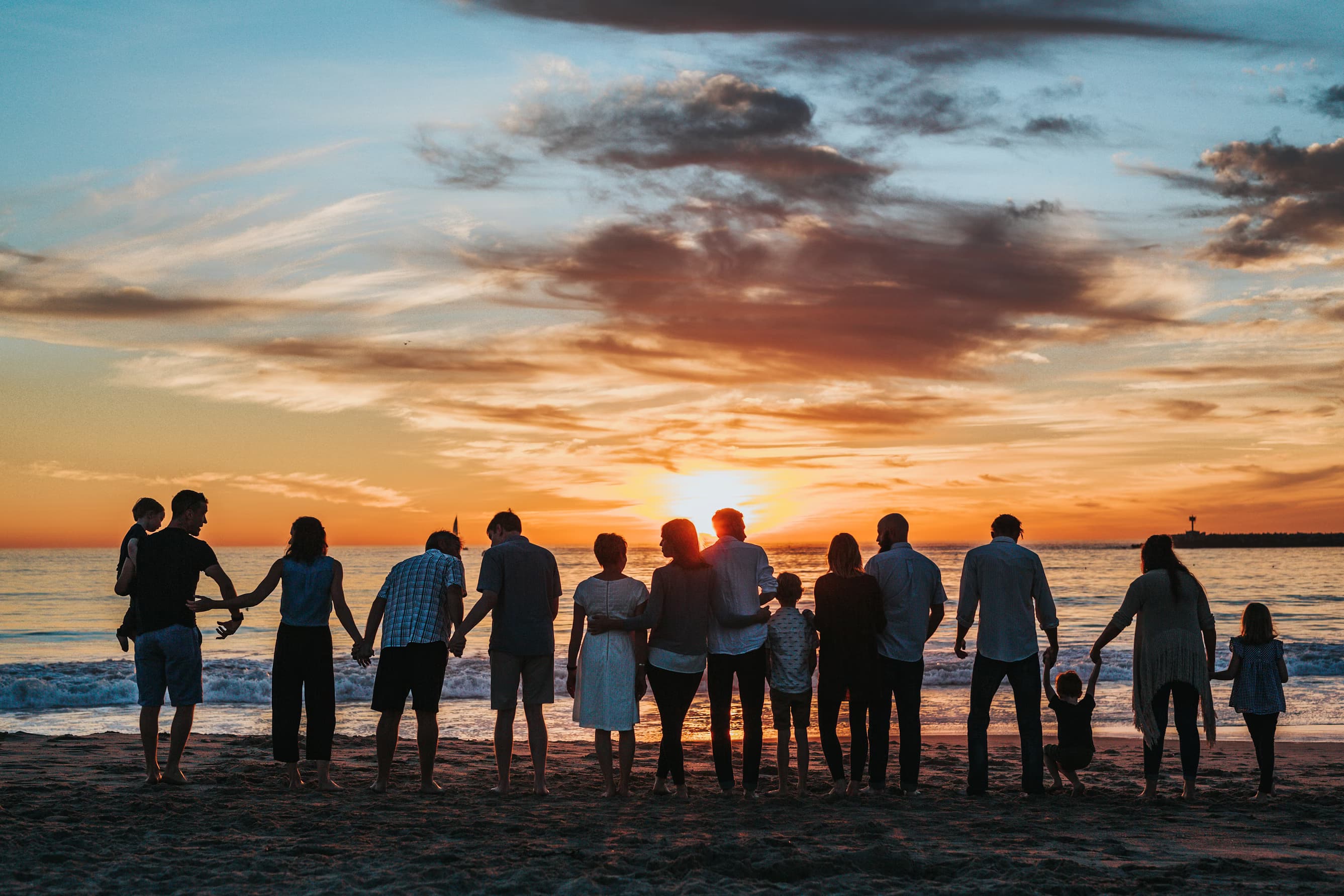 Family running on beach at sunset